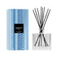 The Nest Blue Cypress & Snow Collection reed diffuser features a patterned glass bottle with black reeds and comes in a blue and white geometric box—ideal for adding a cozy winter scent to your space.