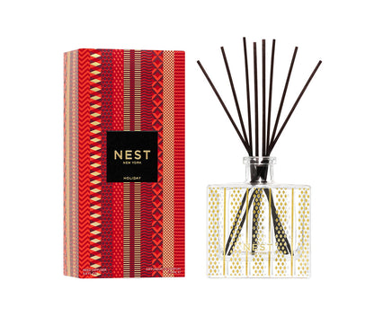 The NEST Holiday Collection reed diffuser by Nest features a patterned glass bottle with black reeds and festive red packaging, bringing the signature Holiday fragrance found in every Nest candle to your home.