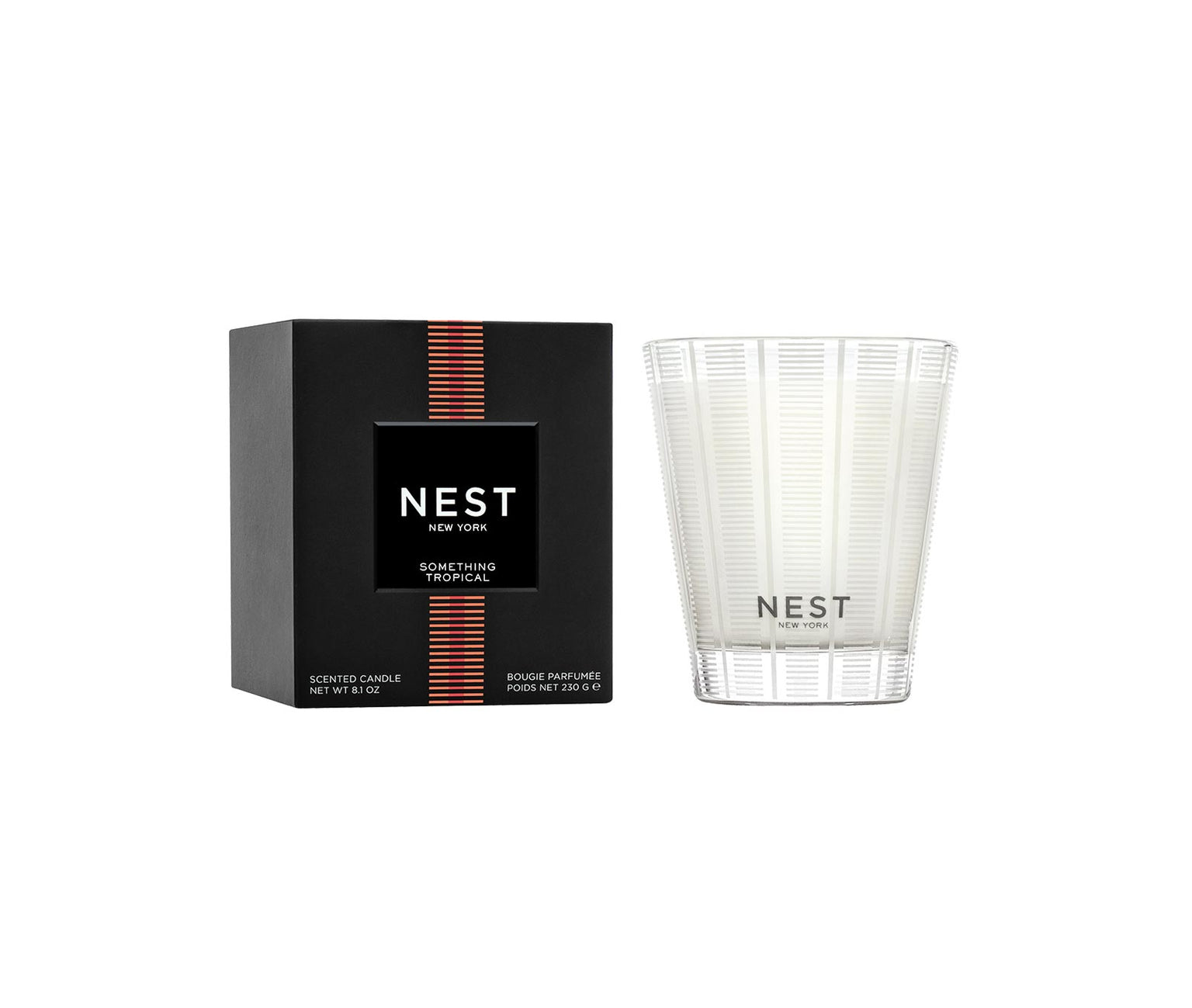 A Nest Something Tropical Candle from the Candle and Diffuser Collection is shown in a white glass container beside its black box, with passion fruit notes delivering a vibrant fragrance.