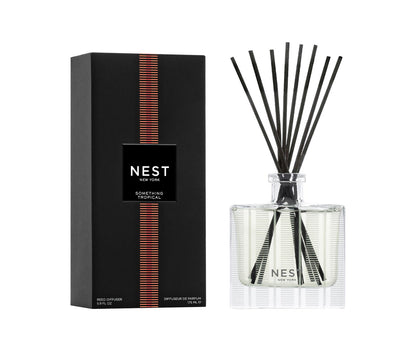 The Nest Something Tropical Candle and Diffuser Collection features a sleek black box and clear reed diffuser, both with matching labels, capturing the essence of passion fruit and cashmere woods.