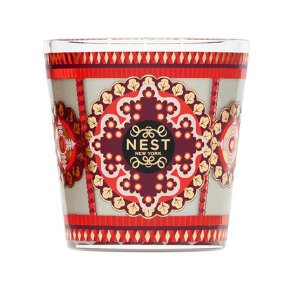 A 3-wick Nest Pierre Marie Holiday Collection pomegranate pine candle in a glass holder featuring a patterned red, gold, and grey design with a central decorative emblem.