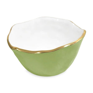 The ENCANTO Collection by Beatriz Ball features a small, round bowl with a light green enamel exterior, white interior, uneven gold-rimmed edge, and subtle gold-toned accents.