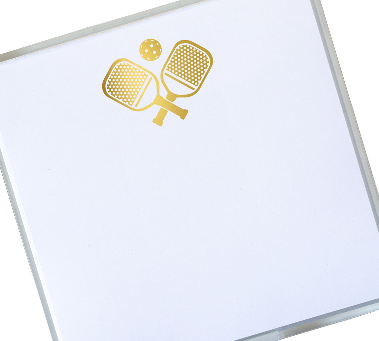 The Black Ink Pickleball Small Paddie is a white notepad with a gold design of crossed pickleball paddles and ball, featuring a velvety smooth surface for a luxurious writing experience.