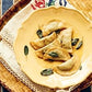 Six dumplings garnished with herbs are arranged on a yellow plate, which rests on a lace-trimmed cloth atop a woven surface—a delightful scene inspired by authentic Italian cuisine, just like the comforting recipes found in Pasta Grannies: Comfort Cooking from Chronicle Books.
