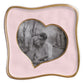 Black-and-white photo of a smiling couple in a park, displayed in the Beatriz Ball Encanto Curved Heart Frame Collection, 5x5—a pink handcrafted heart-shaped frame with a wavy gold border.