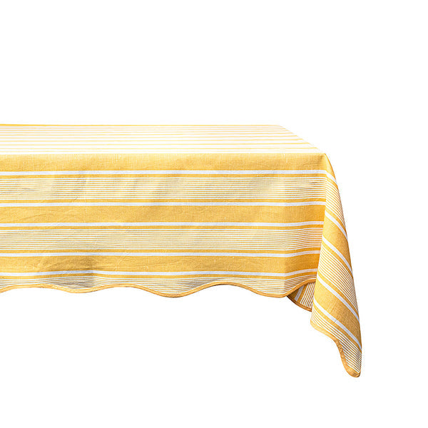 A rectangular table features a gracefully draped Juliska Cabana Stripe Tabletop Collection tablecloth in yellow and white stripes.