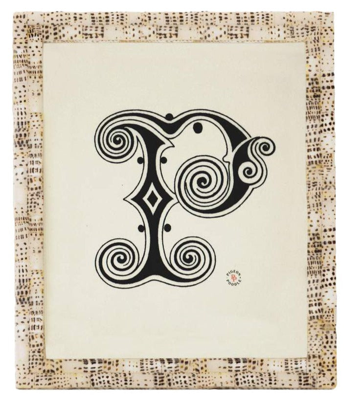 From Pigeon & Poodle’s Mombasa Frame Collection, this framed artwork displays an ornate black and white letter "P" with decorative swirls and geometric patterns on a subway tile-inspired textured background.