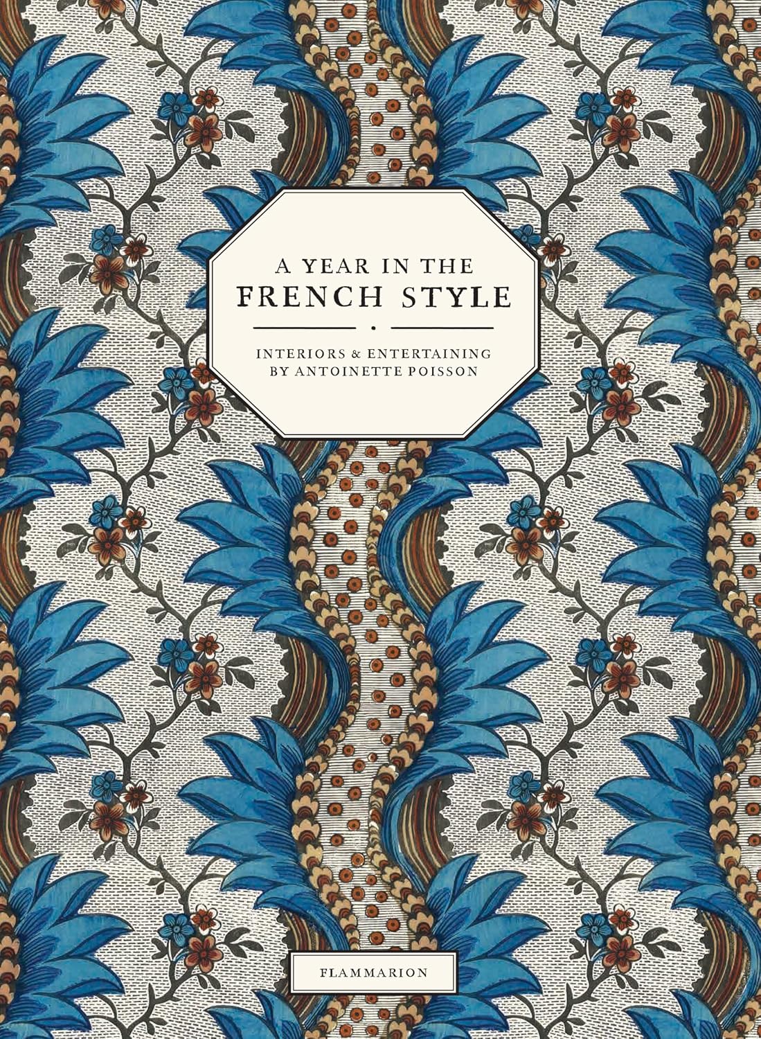 Adorned with a blue and brown floral motif inspired by eighteenth-century wallpaper, the cover of A Year in the French Style by Penguin Random House features a central label and classic domino paper design—an elegant choice for any home decor lover.