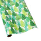 A roll of Caspari’s Christmas Trees with Lights Collection wrapping paper, featuring green and blue tree designs, coordinates perfectly with festive guest towel or triple-ply cocktail napkins.