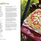 A golden-crusted tomato pie rests on a red and white checkered cloth atop a vibrant red surface outdoors, accompanied by a knife and surrounded by lush green grass, capturing the cozy spirit of recipes featured in The Red Truck Bakery Farmhouse Cookbook from Penguin Random House.