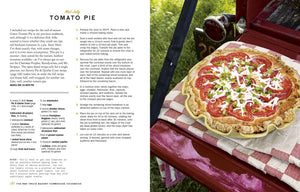 A golden-crusted tomato pie rests on a red and white checkered cloth atop a vibrant red surface outdoors, accompanied by a knife and surrounded by lush green grass, capturing the cozy spirit of recipes featured in The Red Truck Bakery Farmhouse Cookbook from Penguin Random House.