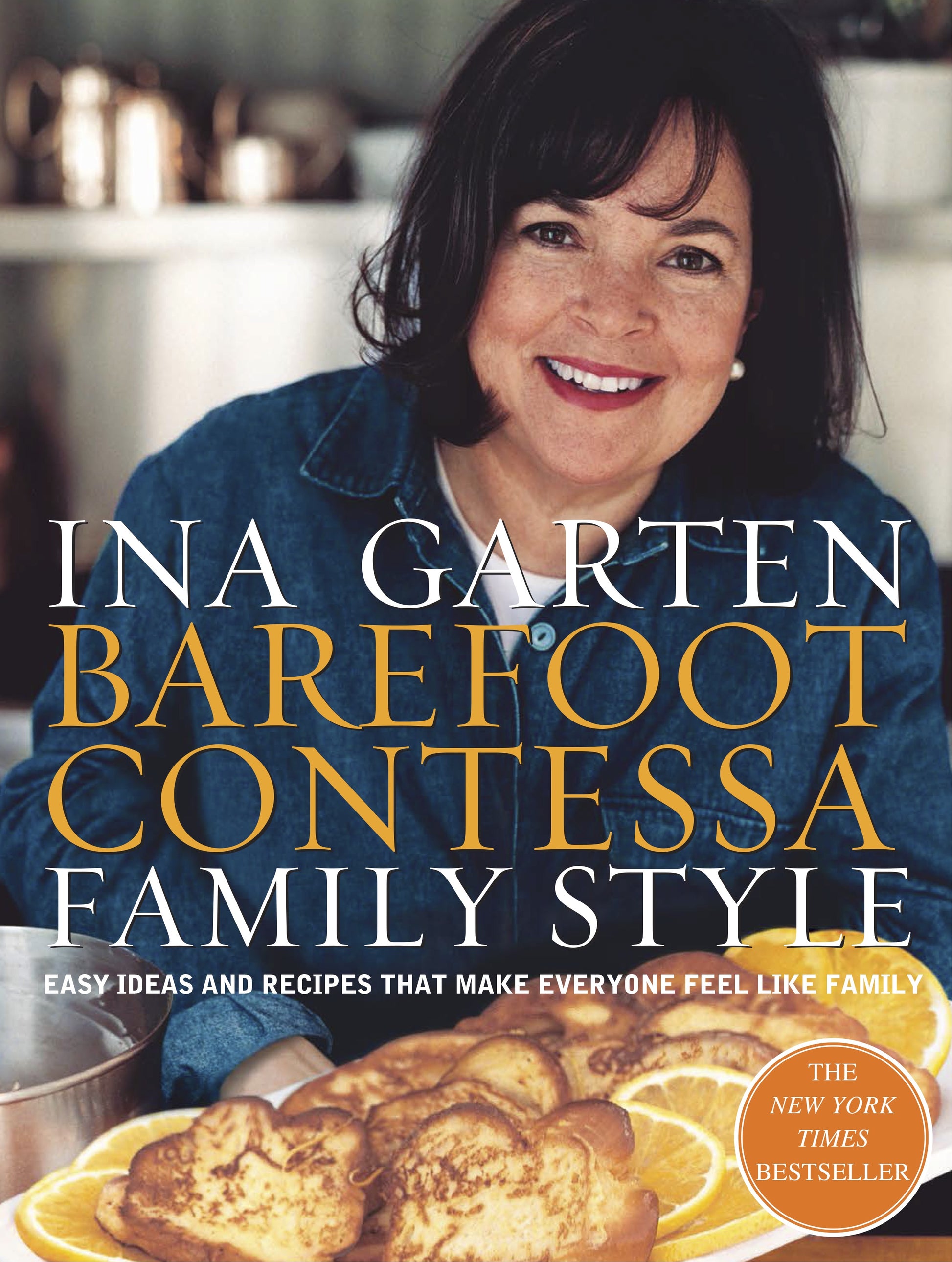Ina Garten beams behind a table displaying a pastry adorned with orange slices; the cover of Barefoot Contessa Family Style by Penguin Random House highlights her distinctive take on approachable, everyday cuisine.