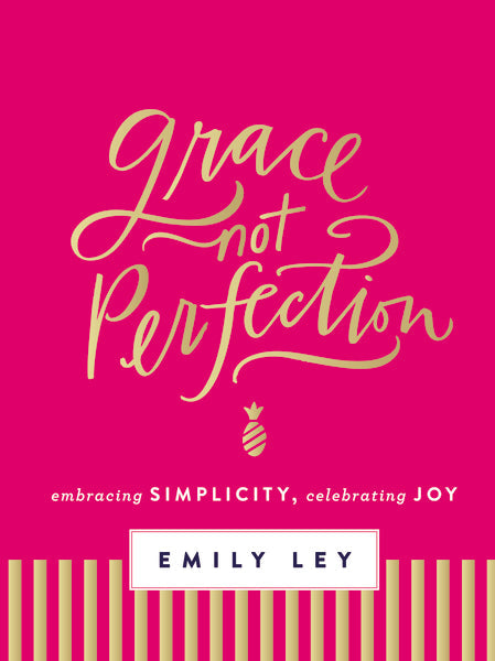 A pink book cover titled "Grace Not Perfection" features gold script, a striped bottom section, and the subtitle "embracing simplicity, celebrating joy to simplify your life." The author is Emily Ley. Published by Thomas Nelson.