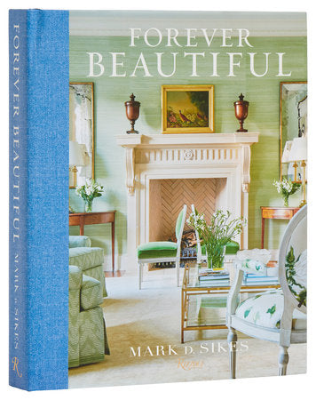 The book "Forever Beautiful: All American Style All Year Long" by Rizzoli showcases an elegant living room with a fireplace, green walls, and classic furniture. This piece offers inspiration and advice on creating beautiful interiors using quintessential American decorating styles.