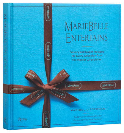 Blue book titled "Mariebelle Entertains: Savory and Sweet Recipes" by Rizzoli, features chocolate desserts and entertaining recipes with text by Lunella Brennan, photography by Mark Roskams, and authored by Maribel Lieberman; includes a brown ribbon design.