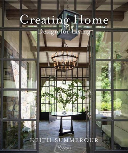 Book cover of “Creating Home, Design for Living” by Rizzoli, a renowned architecture book, showcasing a glass-walled room with a round table and chandelier, overlooking an outdoor view that reflects the timeless charm of Southern homes.