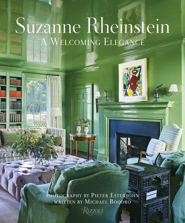 Cover of "Suzanne Rheinstein: A Welcoming Elegance" by Rizzoli featuring a green-painted living room with cozy furniture and a fireplace, blending contemporary flair with classic interior design details.