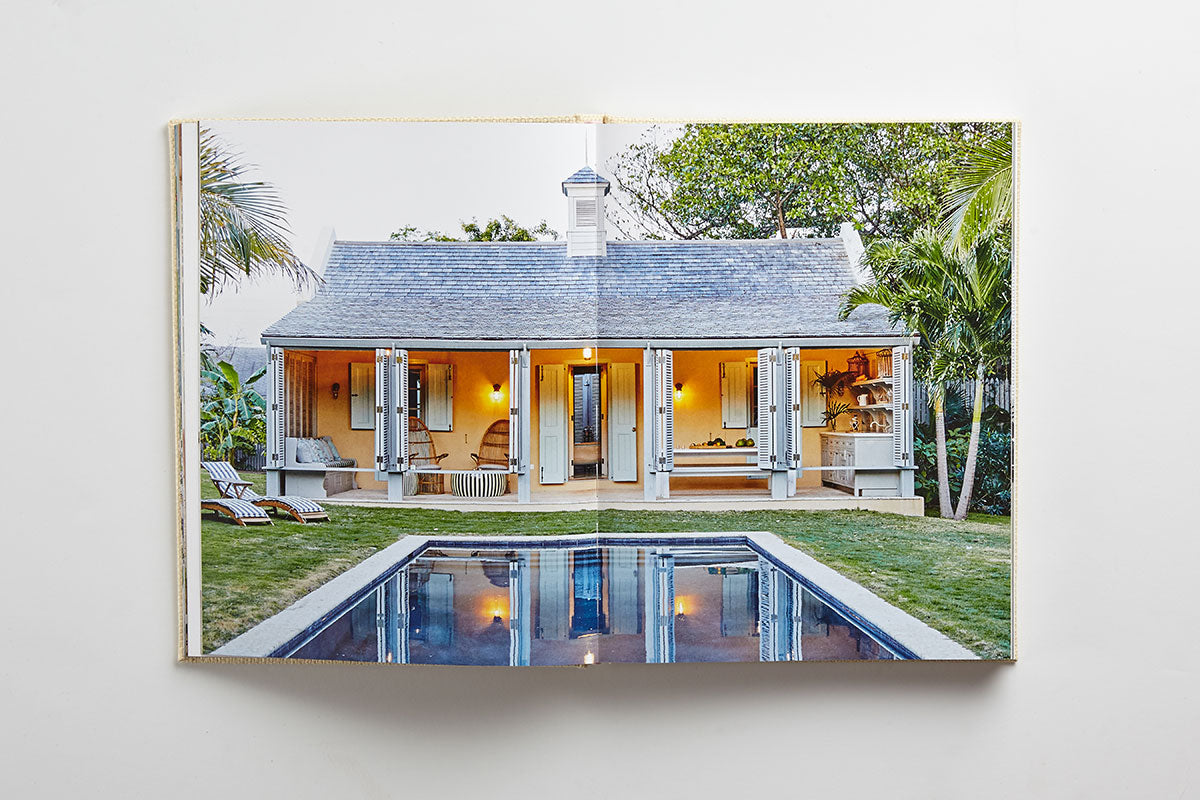 Open book showing a photo of a small house with open shutters, a patio, and a rectangular pool in a green yard with palm trees—a serene scene that perfectly captures the relaxed elegance of island living as featured in “Island Hopping” by Common Ground.