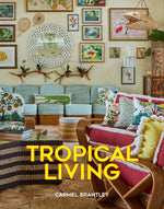 The Tropical Living room design features rattan sofas and chairs, vibrant botanical art, a white circular mirror, and patterned pillows.
