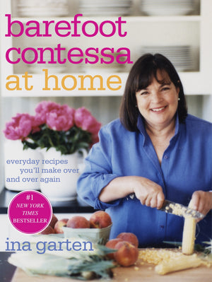 Ina Garten beams as she slices corn on the cover of “Barefoot Contessa At Home” by Penguin Random House, surrounded by fresh peaches and pink flowers—a charming preview of the relaxed, elegant style she brings to her East Hampton kitchen.