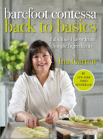 A woman with dark hair smiles while slicing apples in her kitchen, an open copy of “Barefoot Contessa Back To Basics” by Penguin Random House beside her—a perfect source of inspiration for easy home cooking.