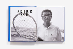 A black-and-white photo of tennis legend Arthur Ashe holding a racket spreads across two pages of the open book "US Open: 50 Years of Championship Tennis" by Abrams, celebrating iconic championship moments.