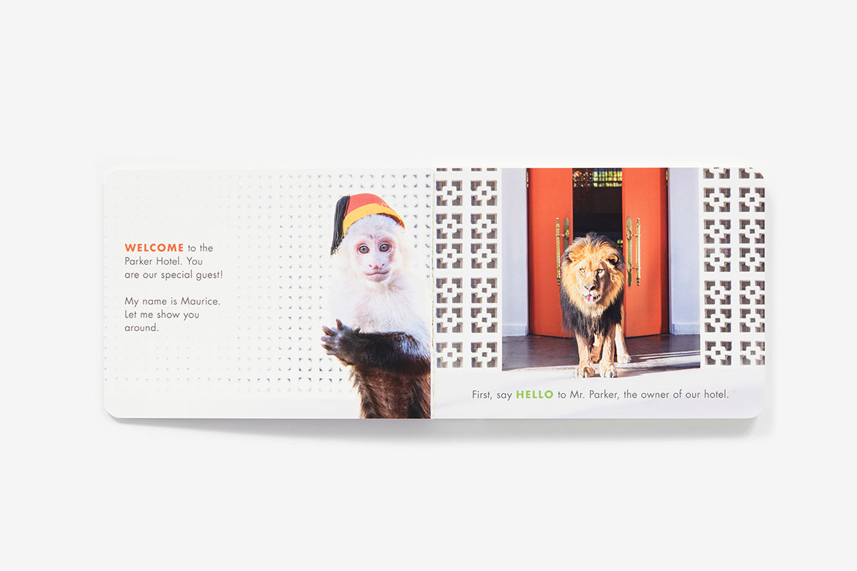 A capuchin monkey in a bellhop hat stands with a lion in a doorway in the Be Our Guest! book, welcoming a guest to the Parker Palm Springs hotel.