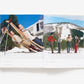 An open book from Abrams' "Slim Aarons: Style" shows glamorous personalities reclining on a sled on the left page and four people standing with skis against a snowy mountain backdrop on the right, capturing the essence of Slim Aarons' iconic fashion photography.