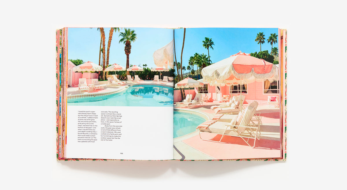 An open book, "The Maximalist: Colorful Interiors for Bold Living" by Abrams, displays a pastel pink poolside scene with lounge chairs, umbrellas, palm trees, and blue sky beside a page of text—offering vibrant home decor inspiration.