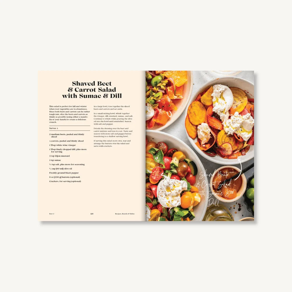 An open copy of *Tables & Spreads* from Chronicle Books features a recipe for shaved beet and carrot salad with sumac and dill on the left page, while the right displays a photo of beautifully styled, colorful salad bowls.