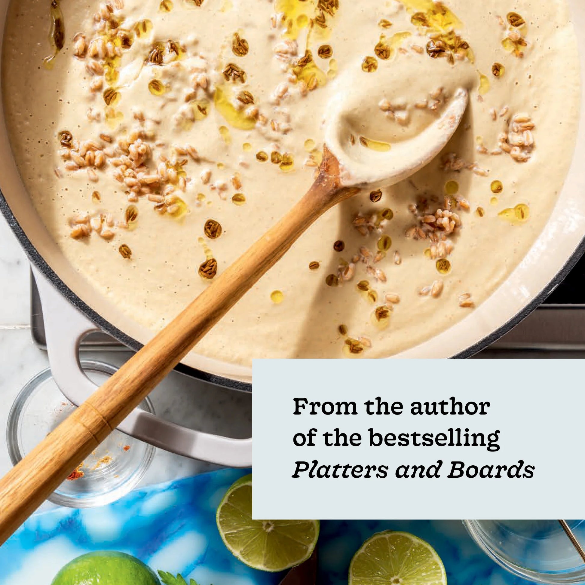 A creamy soup with grains and oil is stirred in a pot with a wooden spoon, offering just one example of the easy soup recipes featured in Every Season Is Soup Season by Chronicle Books. A text overlay reads, “From the author of the bestselling Platters and Boards.” Lime slices and a glass nearby hint at even more healthy recipes waiting to be discovered in this inspiring soup cookbook.