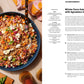 A bowl of farro salad with vibrant vegetables and crumbled cheese sits on a table next to serving utensils and a wedge of citrus; beside it, the Chronicle Books cookbook Every Season Is Soup Season lies open, displaying a healthy soup recipe.