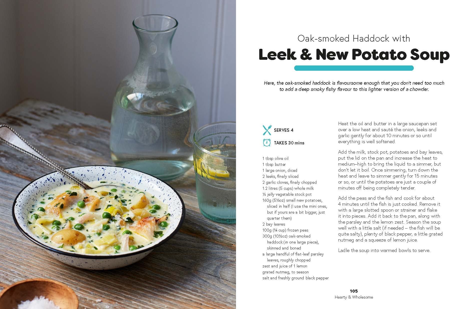 A bowl of leek and new potato soup with smoked haddock sits on a speckled plate, garnished with herbs; a spoon, bread, and a glass of water are nearby on a light table—an inviting scene inspired by nourishing recipes from *Seriously Good Soups* by Chronicle Books.