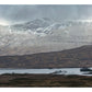 A wide, misty landscape with rolling hills, snow-dusted mountains in the distance, and a lake dotted with small islands evokes the tranquil beauty associated with historic Scottish settings—where celebrated single malt Scotch is made—just like those featured in “Scotch” from Penguin Random House.