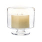 The Nantucket Hurricane Collection by Simon Pearce features a three-wick white candle in a clear glass holder with a short pedestal base, inspired by classic trifle dishes.