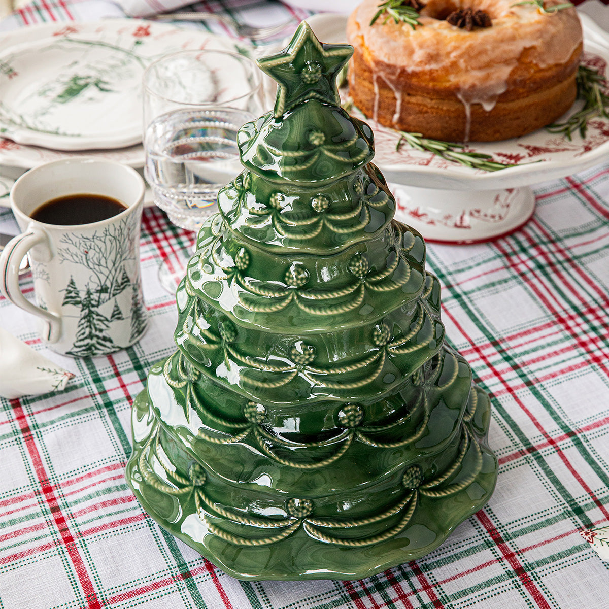 The Juliska Berry & Thread Basil Christmas Tree Cookie Jar makes a charming centerpiece on a plaid tablecloth, surrounded by Berry & Thread holiday dishes, cake, and coffee.