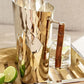 The ezrad Bamboo and Stainless Steel Decor Collection features a hammered stainless steel pitcher with a wooden handle, displayed on a tray beside lime wedges and an iced water glass, bringing modern elegance to any setting.
