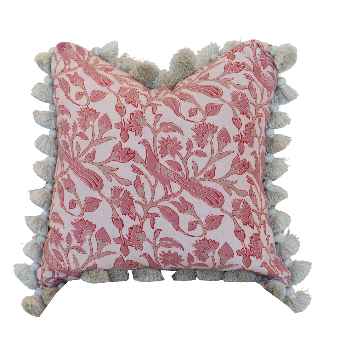 The Peacock Garden Pillow by Hive Custom Pillows is a square cushion adorned with a pink floral pattern and finished with beige tassels along the edges. It features a hidden zipper closure for a seamless look and is photographed against a white background.