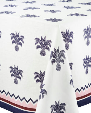 The Ananas Blue Tablecloth by Aquazzura Casa features luxurious linen with a repeating navy blue pineapple motif and elegant zigzag borders in navy and muted red.