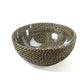 The Calaisio Round Bowl Collection features a round glass serving bowl with a woven crisscross pattern in brown and gold, inspired by traditional design and set against a white background.