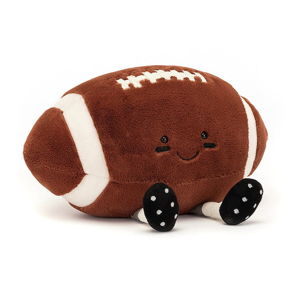 A brown and white stuffed football with white stripes and a smiley face by Jellycat.