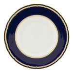 The Ashbourne Navy Dinnerware Collection by Royal Crown Derby features round porcelain plates with a wide dark blue border, gold trim, and a white center, showcasing British craftsmanship.