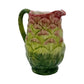 From the Les Ottomans Artichoke Decor and Serveware Collection, this hand-painted ceramic pitcher resembles an artichoke in green and reddish hues with a side handle—a charming Italian tableware piece.
