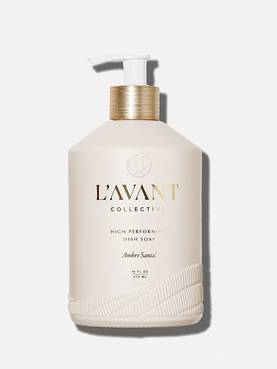 A beige bottle of L’Avant Collective Ambre Santal dish soap with a pump dispenser, labeled “High Performing Dish Soap” and featuring a sophisticated sandalwood fragrance.