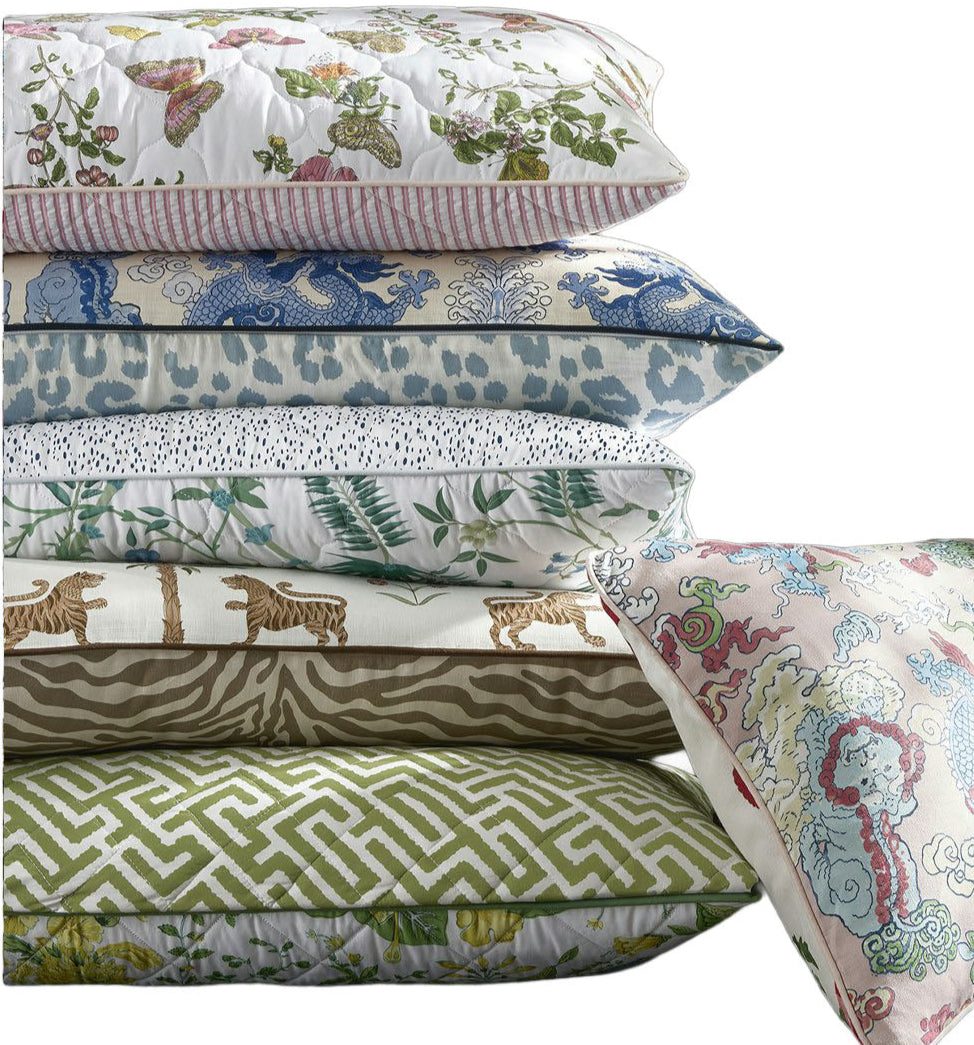 The Reversible Lumbar Pillow Collection by Matouk features six pillows with colorful patterns—florals, animals, prints, geometrics, and abstracts—some accented with piped edges and hidden zippers for a polished touch.