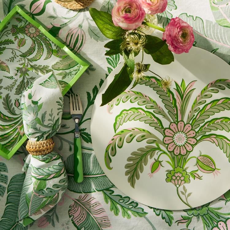 A chic Palm Beach table setting featuring Addison Ross's Palm Beach Scallop Tray Collection in green and pink florals, paired with a plate, napkin, fork, and a pink-white bouquet on a matching cloth for stylish décor flair.