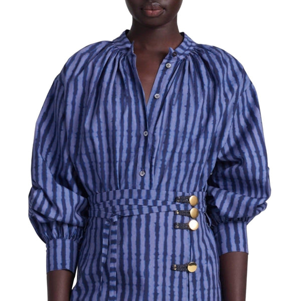 Person wearing an Altuzarra Teresa Top, a blue and white striped blouse with buttons on the side and gathered balloon sleeves. Only the upper torso is visible, showcasing the relaxed fit of the stylish top from Altuzarra.