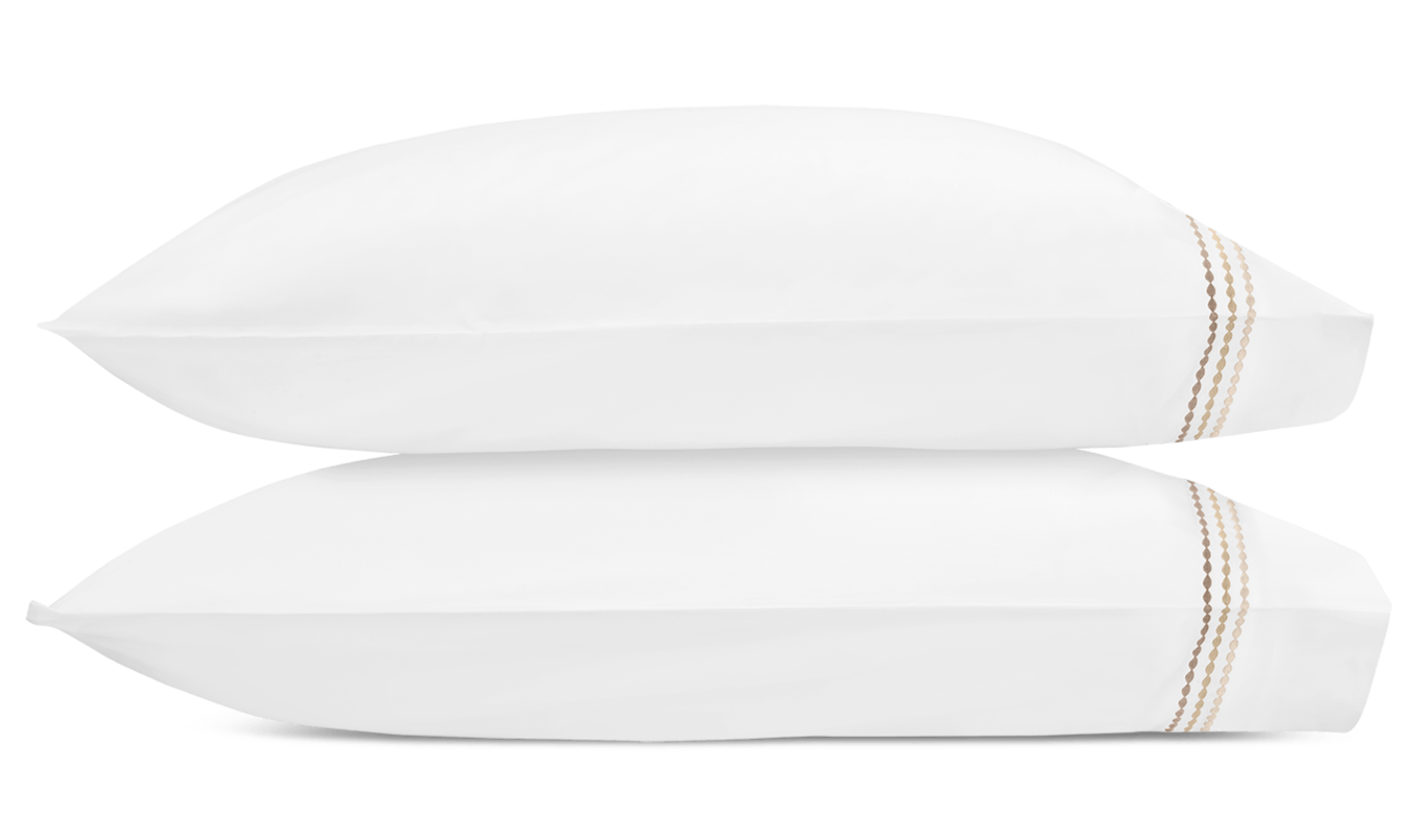 Two white pillows from the Amara Pearl Bedding Collection, Beach by Matouk, are stacked horizontally. Each features a simple brown embroidered detail on one end and is set against a plain white background.