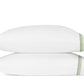 Two white pillows from the Matouk Amara Triple Pearl Bedding Collection are stacked together, each crafted from luxurious sateen and finished with a green and black striped trim along the right edge.