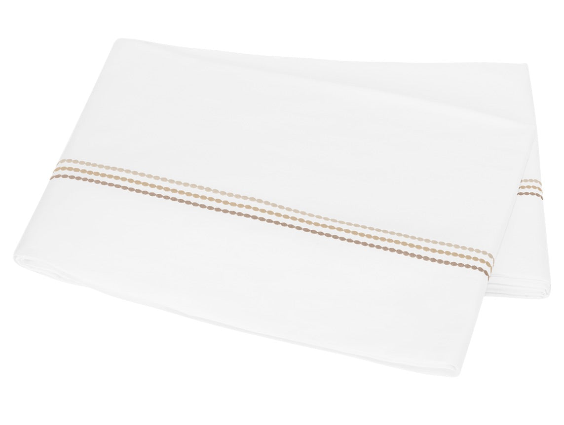 A folded white bedsheet from the Amara Triple Pearl Bedding Collection by Matouk, crafted from luxurious sateen and adorned with an elegant embroidered horizontal stripe of small beige and brown dots near one edge, displayed on a plain background.